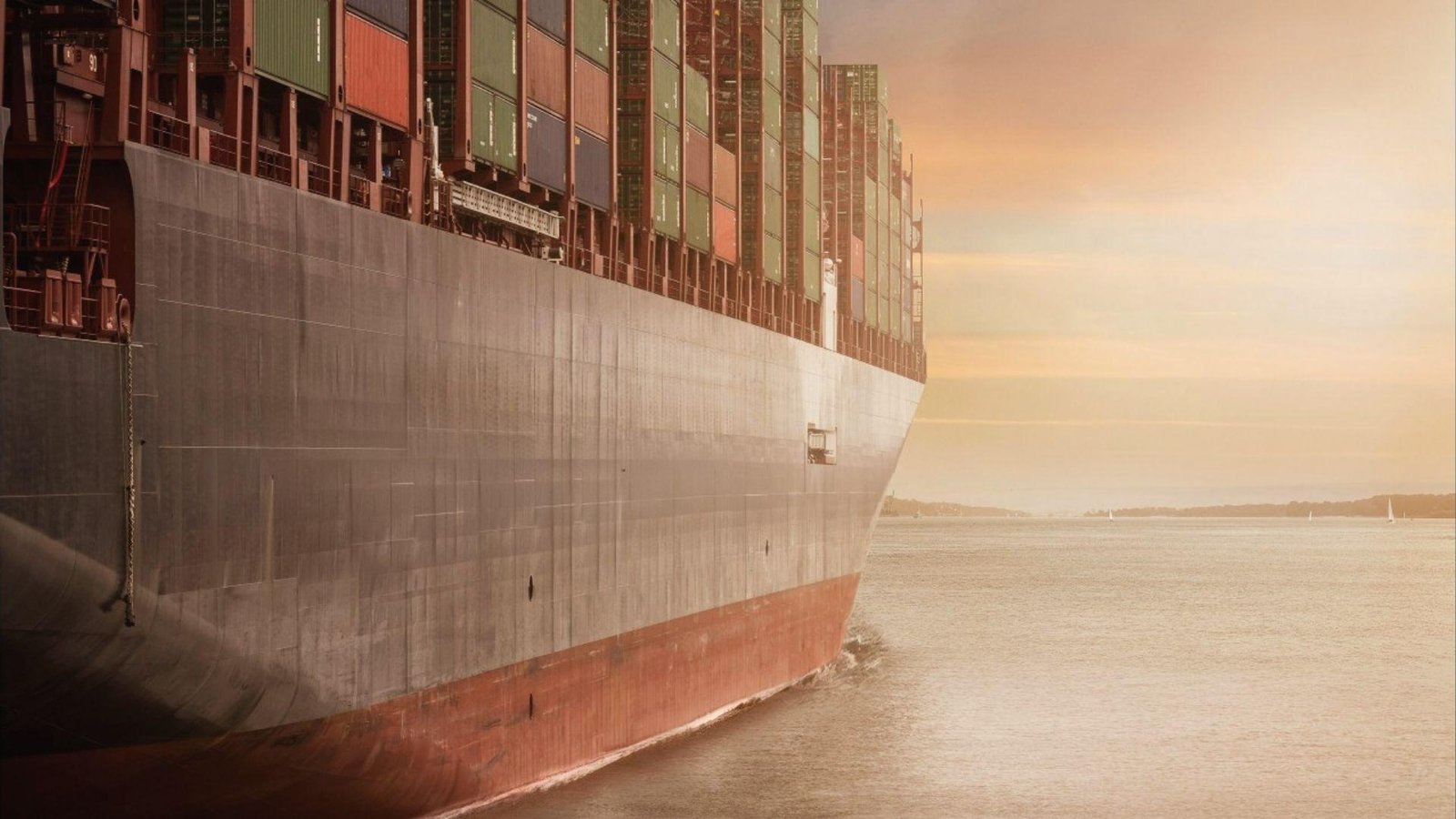 Cargo ship hull at sea carrying stacked containers, showing bulk commodity transport by ocean freight.