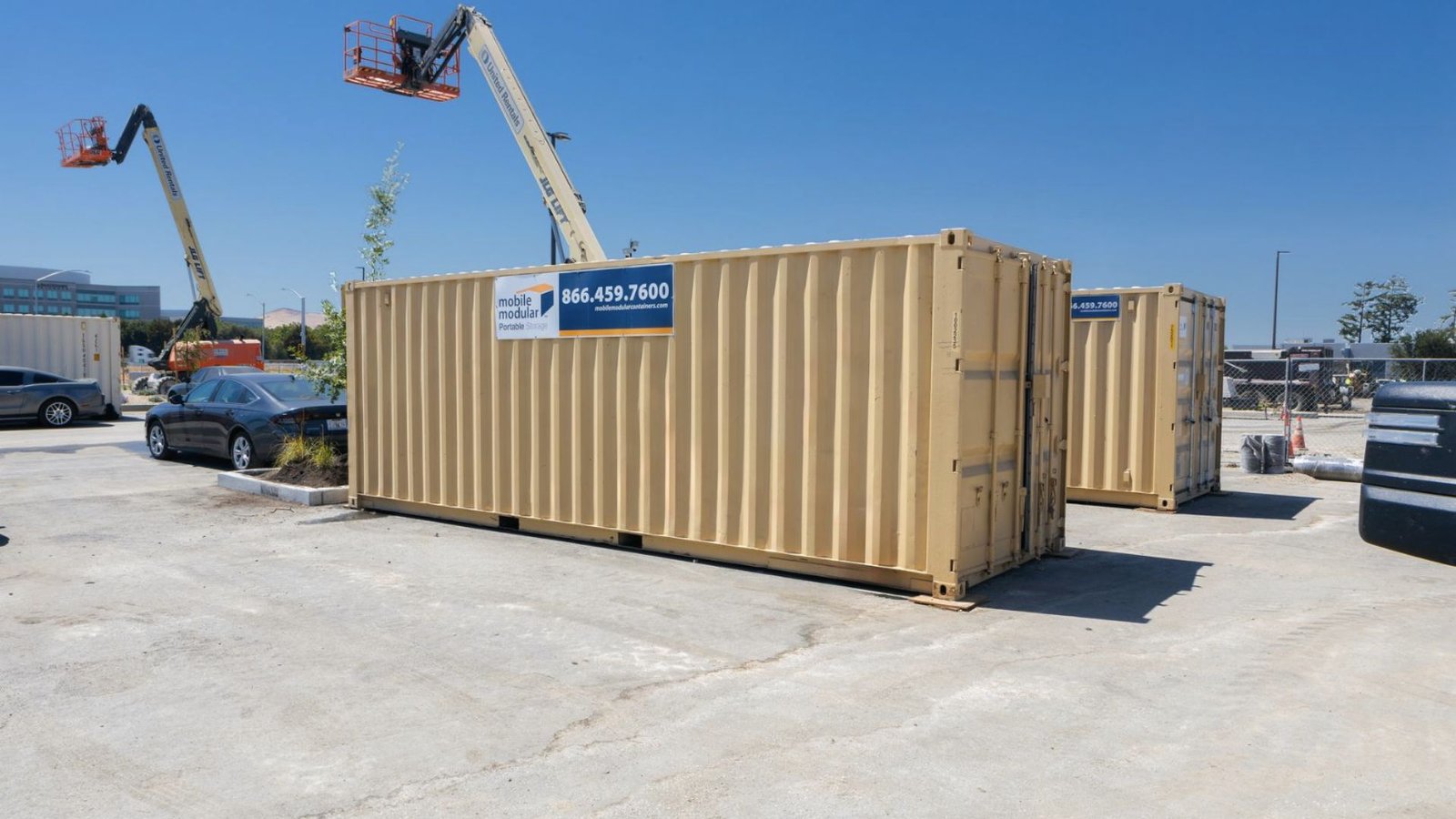 Two beige portable storage containers with “mobile modular” signage on a construction site.