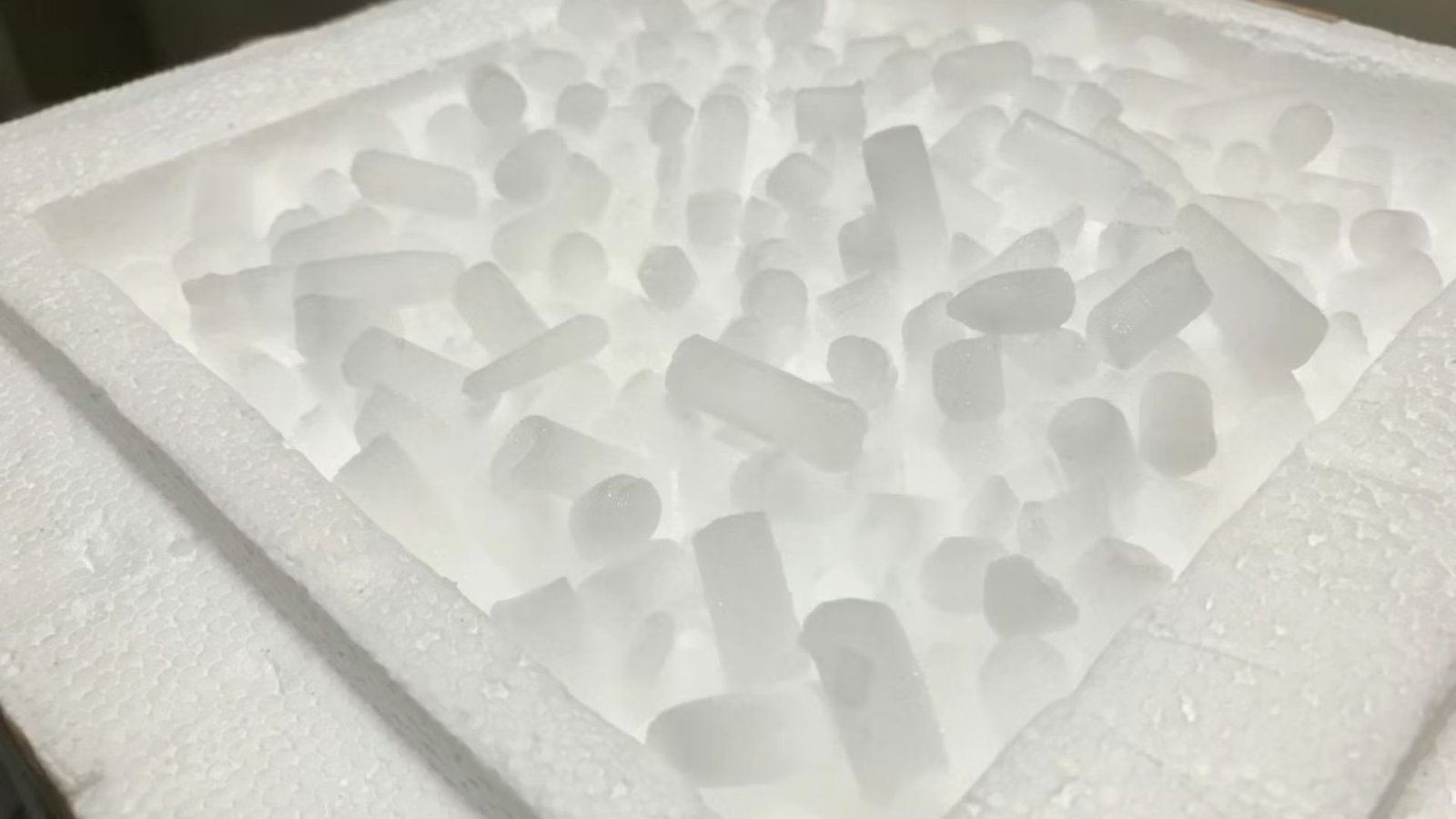 Close-up of dry ice pellets filling a white styrofoam shipping container.
