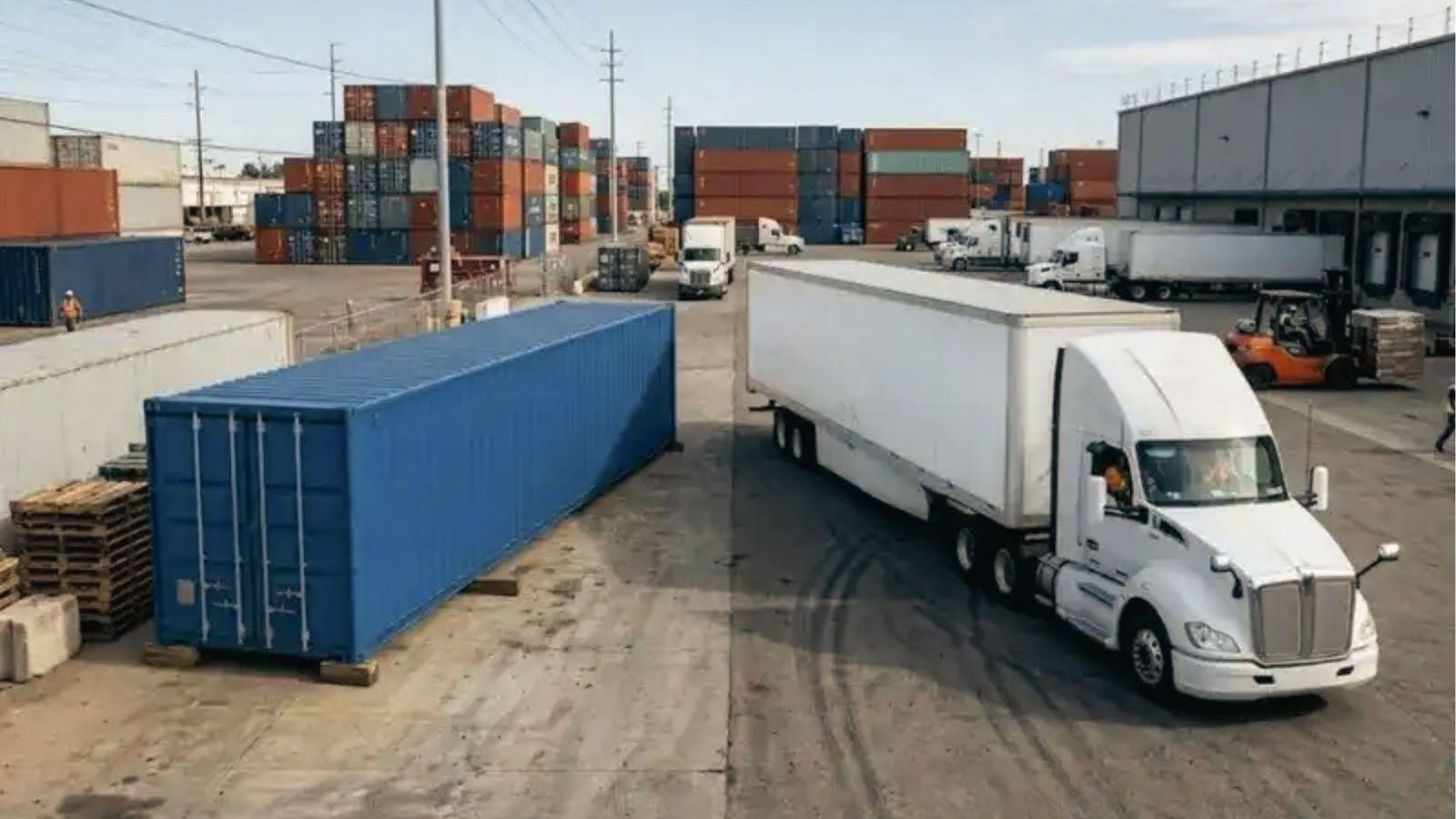 White truck and blue shipping container in busy freight yard, calculate ground transport expenses