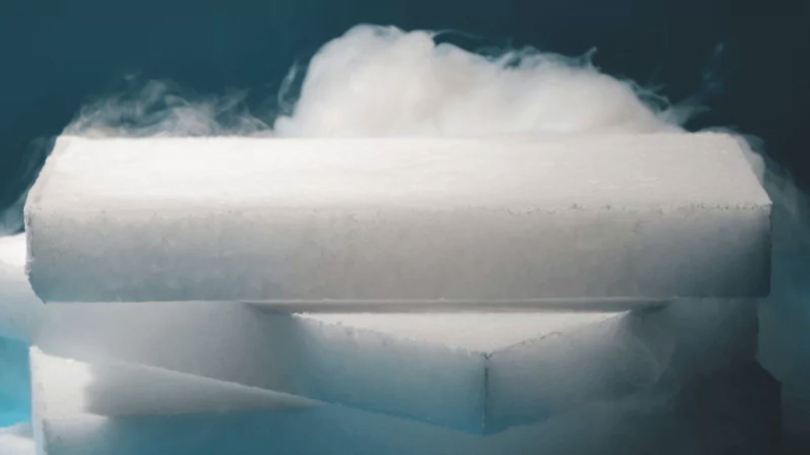 Stacked slabs of dry ice releasing cold vapor against a dark background.