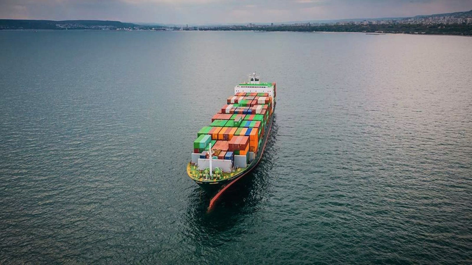 Aerial view of a container ship carrying international freight, managed by an Importer of Record to meet destination import regulations.