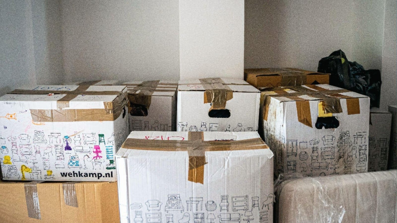 Sealed moving boxes taped and labeled in a room showing items packed for short or long-term moving storage
