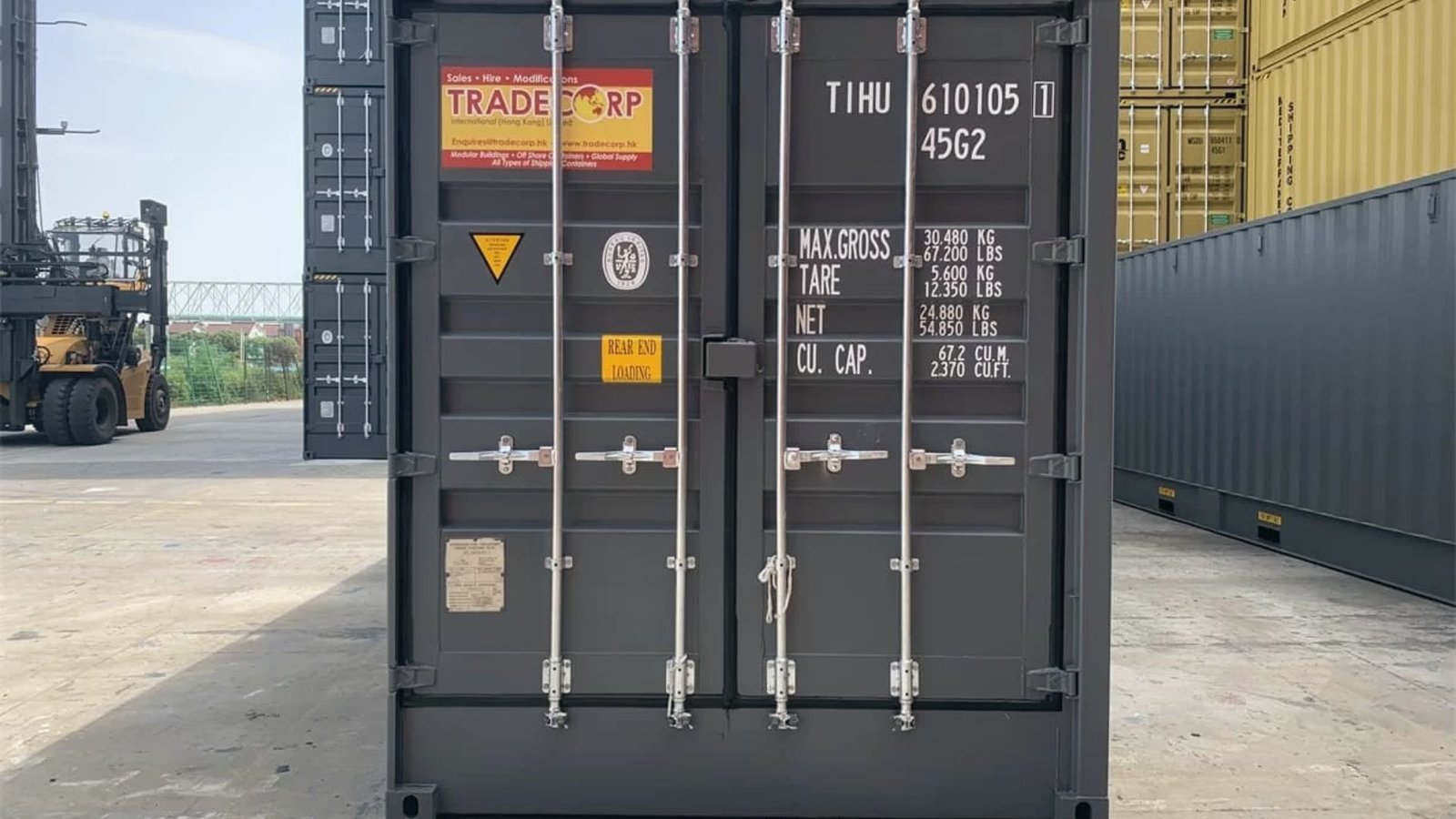 Dark gray 40ft high cube container showing rear doors, Tare and Max Gross markings at a port.