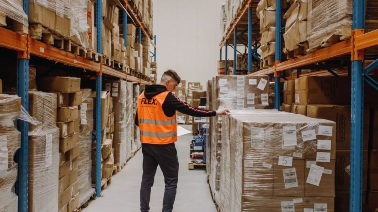 Warehouse staff inspects shrink-wrapped imported pallets, as the Importer of Record ensures proper classification and storage of foreign goods.