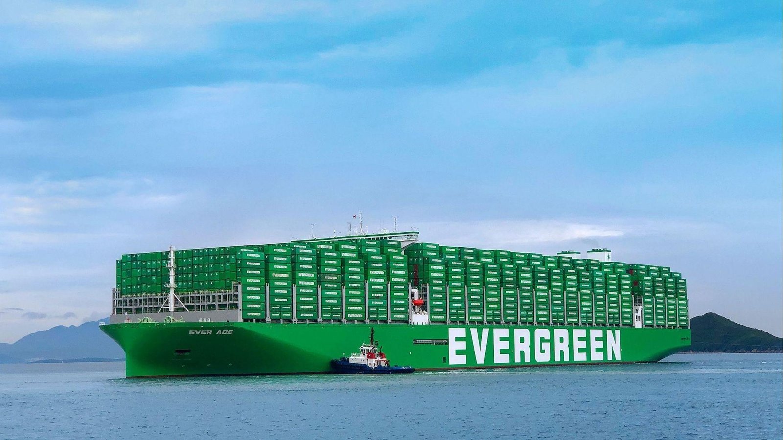 Ever Ace Evergreen ship in green sailing near mountains with tugboat, record TEU capacity vessel