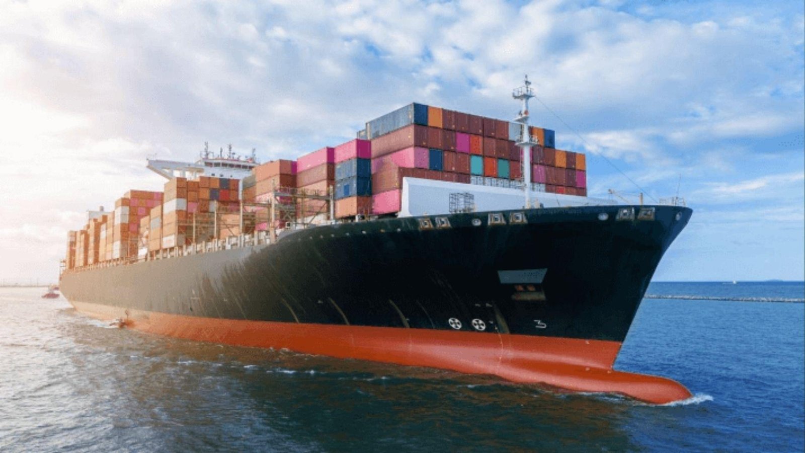 Loaded container ship sailing under clouds, illustrating global trade of commodities via sea shipping.