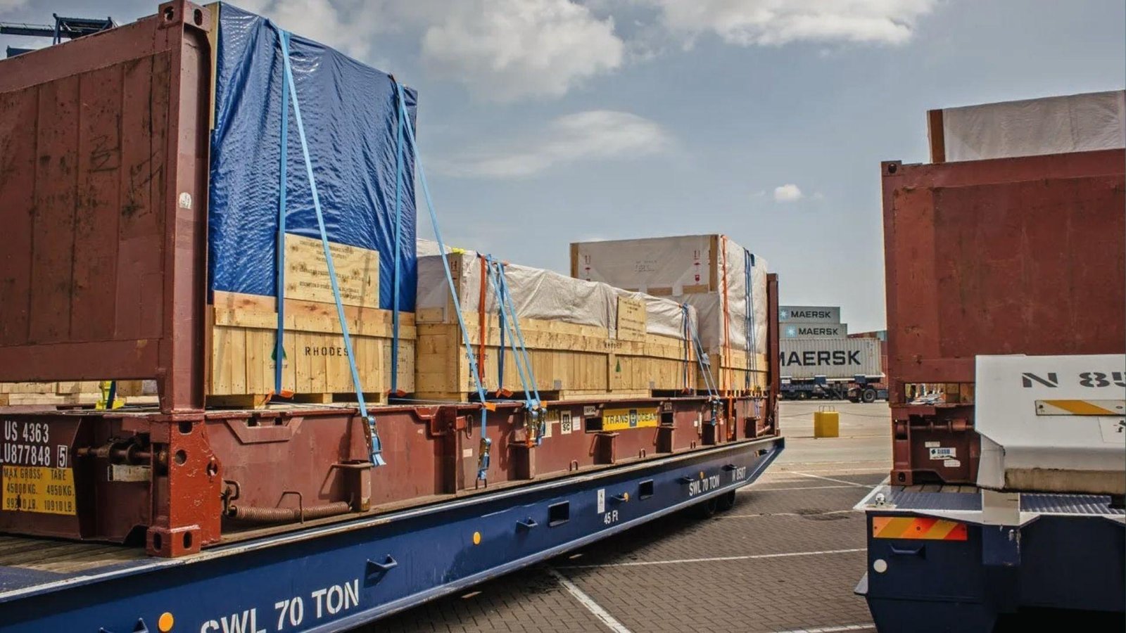 Secured crated commodity on flat rack container at port, ready for specialized shipping transport.