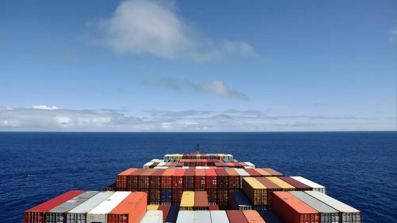 Containers stacked on ship deck mid-ocean, highlighting commodity cargo in global supply chain routes.